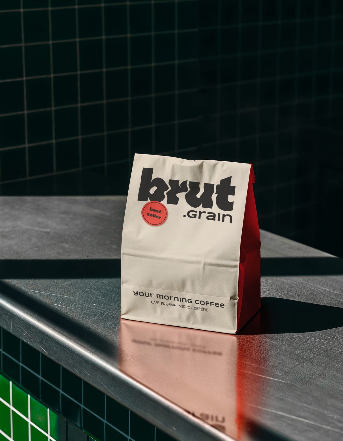 Sac brut.grain de 1 kg posé sur un carrelage vert sombre